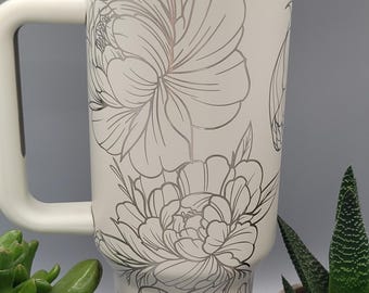 May include: A white stainless steel travel mug with a floral design. The mug has a lid with a flip top and a handle.