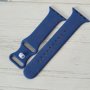 May include: Two navy blue watch straps with a whale shark pattern. The straps are made of a flexible material and feature a repeating design of whale sharks. The straps are designed to fit a smartwatch.