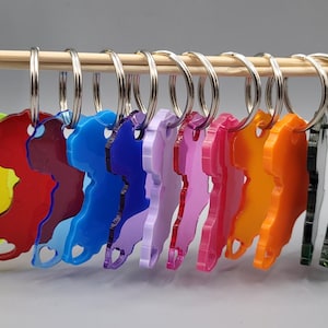 Puede incluir: Un conjunto de 14 llaveros coloridos con forma del continente africano. Los llaveros están hechos de acrílico y tienen una variedad de colores, incluyendo negro, amarillo, rojo, azul, morado, rosa, naranja y verde.
