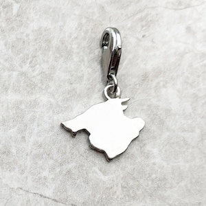 May include: Silver charm in the shape of the island of Mallorca, Spain. The charm has a lobster clasp for attaching to a bracelet or necklace.