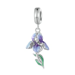 Pode incluir: Berloque de prata com uma flor de íris de esmalte roxo e azul com um caule e folhas verdes. O berloque tem um cristal transparente no centro da flor.