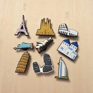 May include: A collection of colorful travel-themed charms featuring iconic landmarks. Includes the Eiffel Tower, Sagrada Familia, Colosseum, Statue of Liberty, Leaning Tower of Pisa, and more. Perfect for decorating shoes or accessories.