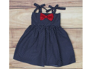 May include: A navy blue polka dot dress with red bow tie straps. The dress has a fitted bodice and a full skirt.