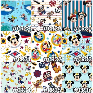 May include: A collection of fabric swatches featuring various Disney characters in nautical and cruise-themed designs. The patterns include Mickey Mouse, Donald Duck, and Goofy, with anchors, stars, and ship wheels. Each swatch is labeled with a code.