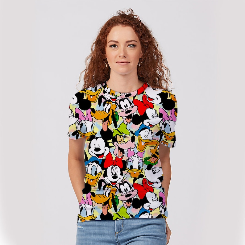 May include: A white t-shirt with a colorful print of various Disney characters, including Mickey Mouse, Minnie Mouse, Donald Duck, Goofy, and Pluto.