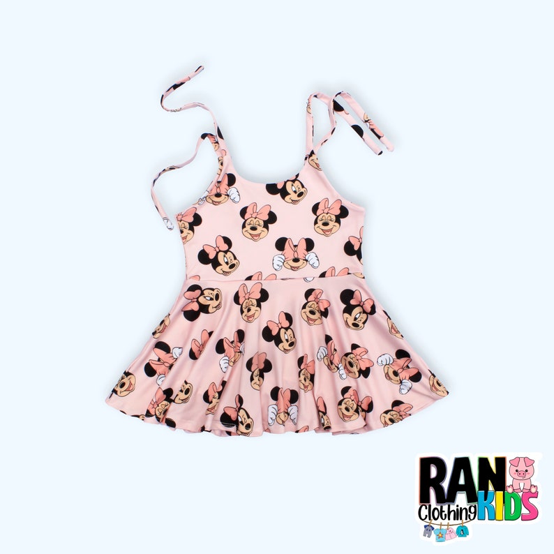 Może przedstawiać: R&oacute;żowa sukienka bez rękaw&oacute;w z nadrukiem Minnie Mouse. Sukienka ma rozkloszowaną sp&oacute;dnicę i regulowane ramiączka.