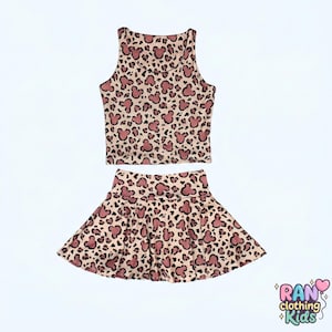 May include: A two-piece outfit featuring a crop top and a flared skirt. The set is patterned with a tan leopard print and pink Mickey Mouse silhouettes. The outfit is designed for children.