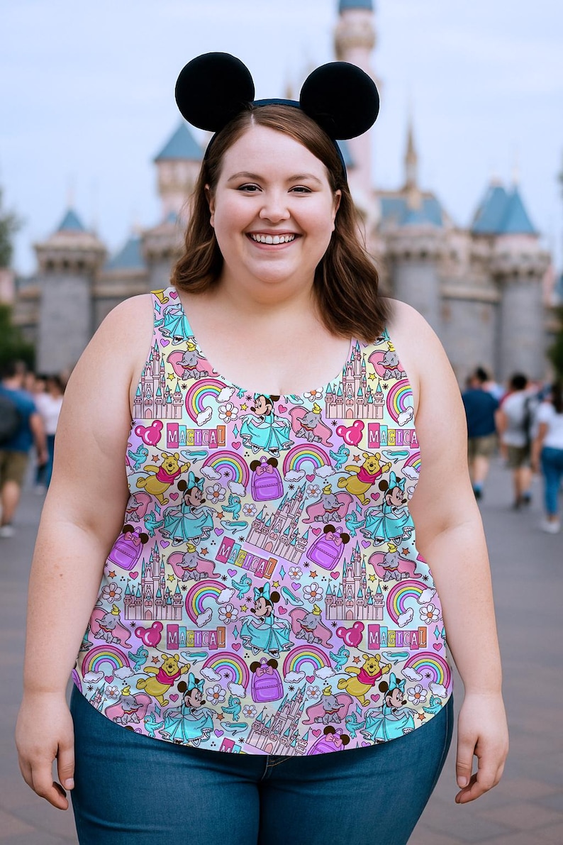 K&ouml;nnte beinhalten: Ein farbenfrohes Tanktop mit einem sich wiederholenden Muster aus Zeichentrickfiguren, Schl&ouml;ssern, Regenbogen und dem Wort "Magical". Das Tanktop wird mit einer blauen Jeans und schwarzen M&auml;useohren getragen. Der Hintergrund zeigt ein Schloss und Menschen.
