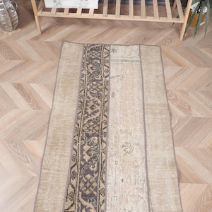 Op de afbeelding: Een beige en bruin patchwork tapijt met een geometrisch patroon. Het tapijt is gemaakt van geweven stof en heeft een verweerde look.