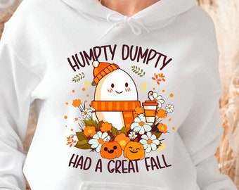 May include: White hoodie featuring a graphic of Humpty Dumpty with a fall theme. The design includes an egg character wearing a hat and scarf, surrounded by pumpkins, flowers, and the text "Humpty Dumpty Had a Great Fall."