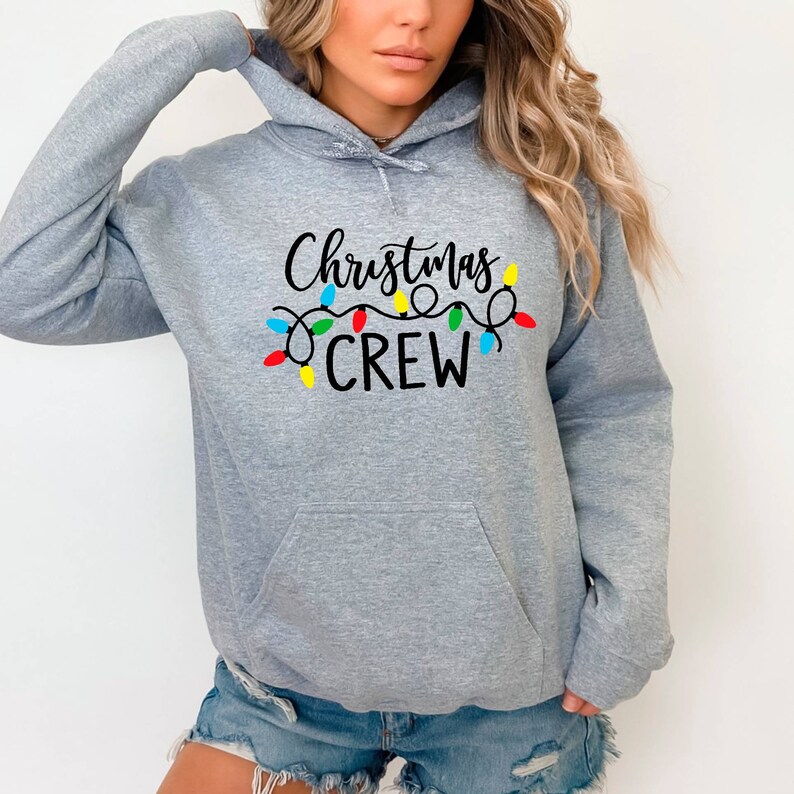 May include: Grey hooded sweatshirt with the text "Christmas Crew" in black lettering and a string of colourful Christmas lights above the text.