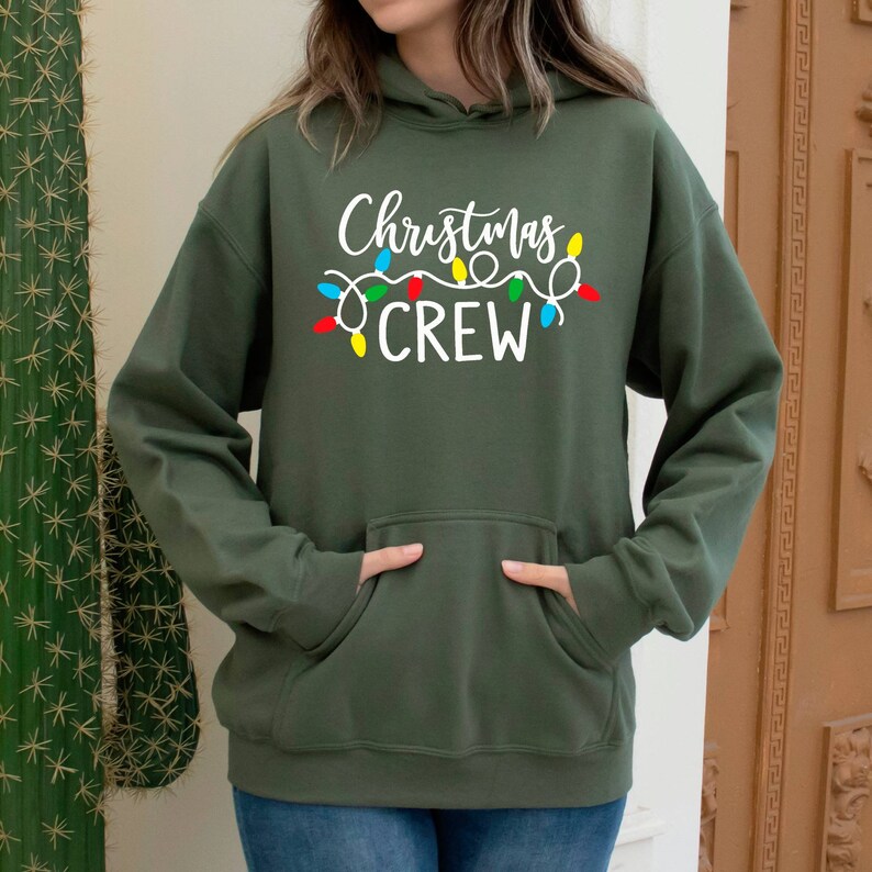 May include: A green hooded sweatshirt with the text "Christmas Crew" in white lettering and a string of colourful Christmas lights above the text.