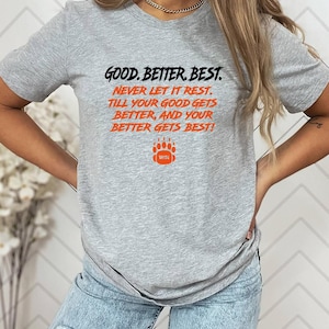 May include: A light gray t-shirt with the text "GOOD. BETTER. BEST. NEVER LET IT REST. TILL YOUR GOOD GETS BETTER, AND YOUR BETTER GETS BEST!" in black and orange. A football graphic with the word "WIN" is below the text.