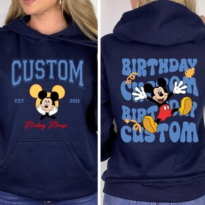 K&ouml;nnte beinhalten: Ein marineblauer Hoodie mit einem Mickey Mouse-Motiv auf der Vorderseite und einem "Birthday Custom"-Motiv auf der R&uuml;ckseite. Das Mickey Mouse-Motiv enth&auml;lt den Text "Custom Est 2011 Mickey Mouse".