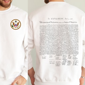 May include: White sweatshirt featuring the US seal on the front and the Declaration of Independence on the back. The text on the back reads "In Congress, July 4, 1776. The unanimous Declaration of the thirteen united States of America."