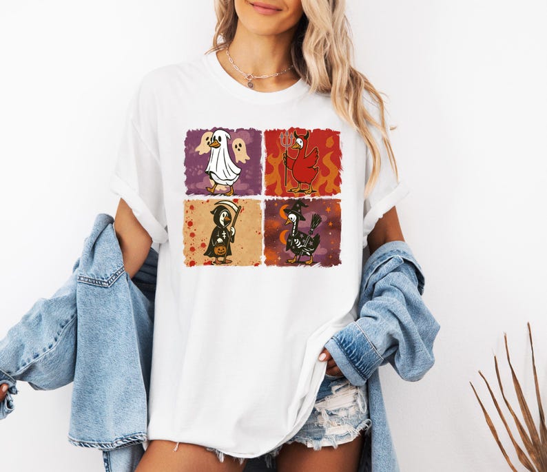 May include: White t-shirt featuring four Halloween-themed chicken illustrations. Each chicken is dressed as a different character: a ghost, a devil, a grim reaper, and a witch. The illustrations are in colorful squares.