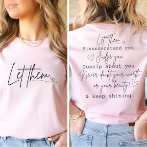 May include: Pink t-shirt with the text "Let them misunderstand you, judge you, gossip about you, never doubt your worth or your beauty! & keep shining!" printed on the back. The front of the shirt has the text "Let them" with a small heart.
