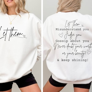 May include: White sweatshirt with the text "Let them" on the front and "Let Them Misunderstand you Judge you Gossip about you Never doubt your worth or your beauty! & keep shining!" on the back.