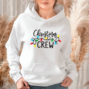 May include: White hooded sweatshirt with the text "Christmas Crew" in black lettering and a string of colourful Christmas lights.