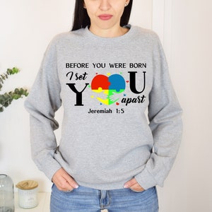 Puede incluir: Sudadera gris con un dise&ntilde;o de pieza de rompecabezas en forma de coraz&oacute;n y el texto "Antes de que nacieras, te apart&eacute; Jerem&iacute;as 1:5".