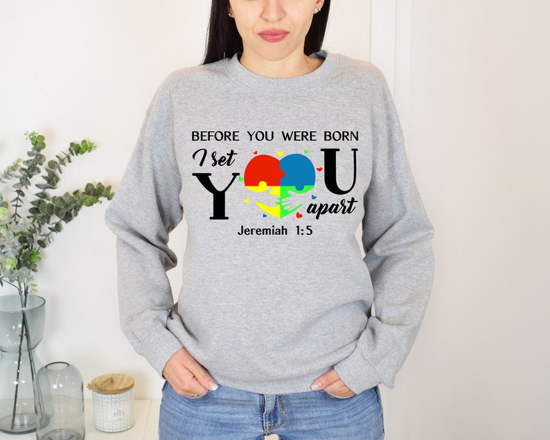 Puede incluir: Sudadera gris con un dise&ntilde;o de pieza de rompecabezas en forma de coraz&oacute;n y el texto "Antes de que nacieras, te apart&eacute; Jerem&iacute;as 1:5".