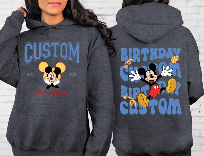 K&ouml;nnte beinhalten: Ein dunkelgrauer Hoodie mit einem blauen und wei&szlig;en Mickey-Mouse-Motiv auf der Vorderseite. Das Motiv lautet "Custom Est 2011 Mickey Mouse". Die R&uuml;ckseite des Hoodies hat ein blaues und wei&szlig;es Motiv mit der Aufschrift "Birthday Custom Birthday Custom".