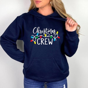 May include: Navy blue hoodie with a white graphic of Christmas lights and the text "Christmas Crew".