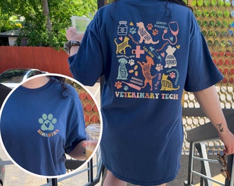Könnte beinhalten: Ein blaues T-Shirt mit einem bunten Grafikdesign aus verschiedenen Tieren und medizinischen Symbolen. Der Text "Veterinary Tech" ist auf das T-Shirt gedruckt. Das T-Shirt hat ein Pfotenabdruck-Design mit dem Namen "Samantha" auf der Vorderseite.