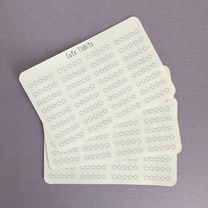 May include: A stack of white stickers with a light purple background. Each sticker has rows of outlined stars. The text "Cute Tidbits" is printed at the top of the top sticker. The stickers are likely for planning or crafting.