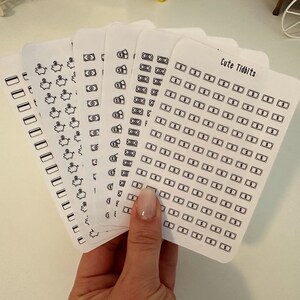 May include: A set of six sheets of stickers featuring various money-themed designs, including piggy banks, dollar bills, and stacks of money. The stickers are printed on white paper and have a black outline. The text "Cute Tidbits" is printed on one of the sheets.