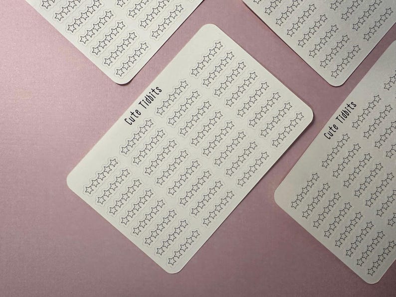 May include: Several white sticker sheets with rows of outlined star shapes. The text "Cute Tidbits" is printed on some of the sheets. The stickers are arranged on a light purple background.