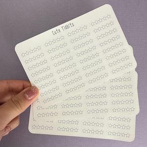 May include: A stack of white sticker sheets featuring rows of outlined star shapes. The text "Cute Tidbits" is printed in black at the top left. The stickers are held against a light purple background.