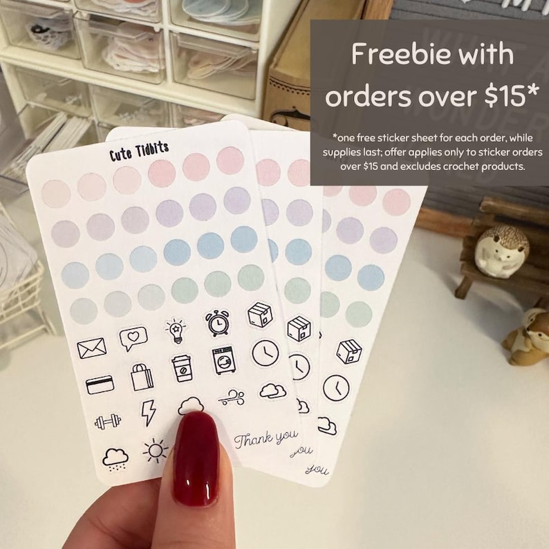 May include: Three sheets of pastel colored dot stickers with a variety of black and white icons including a heart, lightbulb, alarm clock, mailbox, credit card, shopping bag, lightning bolt, cloud, dumbbell, sun, rain cloud, and clock. The text "Cute Tidbits" and "Thank you" are written on the sticker sheets. Freebie with orders over $15* *one free sticker sheet for each order, while supplies last; offer applies only to sticker orders over $15 and excludes crochet products.
