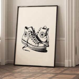 May include: Black and white illustration of a pair of Converse sneakers. The sneakers are drawn in a vintage style and are a classic design.
