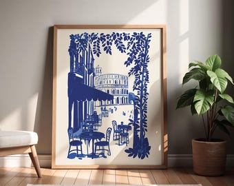 May include: A blue and white illustration of a cafe scene with tables and chairs under a canopy. The cafe is located in a city with a large building in the background. The illustration is framed in a wooden frame.