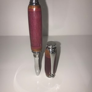 Op de afbeelding: Een houten pen met een zilveren dop en een zilveren punt. De pen is gemaakt van donker hout met een inleg van licht hout. De pen is gesloten en de dop zit erop.