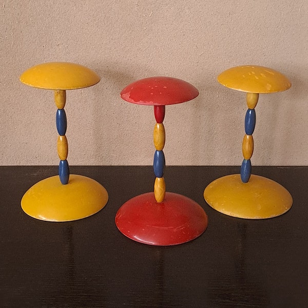 A trio of vintage distressed wooden colorful hat stands