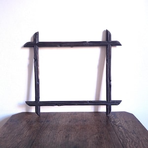 May include: A dark brown, rectangular picture frame with a rustic, twig-like design. The frame is made of dark wood and has a simple, yet elegant, aesthetic. The frame is empty, ready to display a photo or artwork.