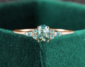 May include: A rose gold ring with a moss agate oval gemstone and smaller green gemstones on the band.