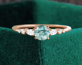 May include: A rose gold engagement ring with a green moss agate center stone and small round diamonds on the band.