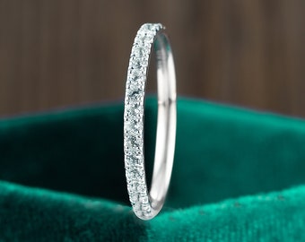 May include: A thin silver band with a row of small, clear gemstones set around the entire band.