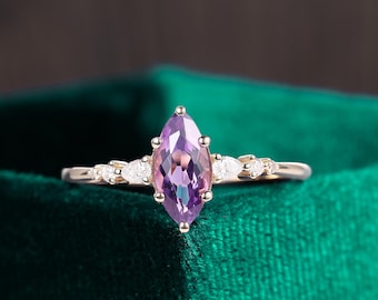 Op de afbeelding: Een verlovingsring met een marquise-vormige amethist, gezet in goud met kleine diamant accenten.