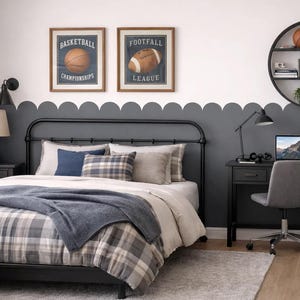 Puede incluir: Dormitorio con estructura de cama de metal negro, ropa de cama a cuadros y manta azul. Dos estampados deportivos enmarcados cuelgan sobre la cama. Un escritorio con portátil y silla está instalado cerca de la cama, y una estantería redonda exhibe la decoración.