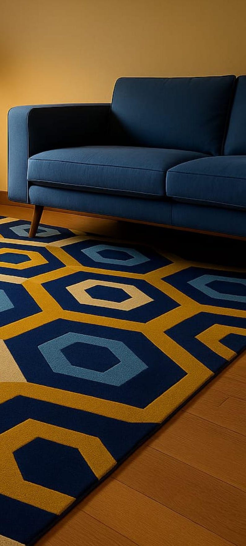 May include: A modern area rug with a geometric pattern in shades of navy blue, light blue, and yellow. The rug is placed on a wooden floor, with a navy blue sofa in the background.
