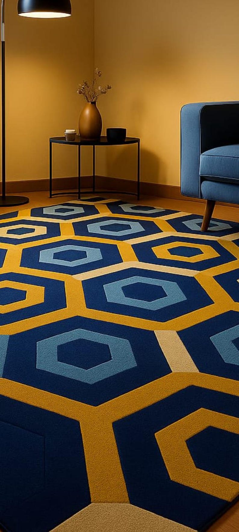 May include: A geometric patterned rug in a room setting. The rug features a repeating pattern of blue, yellow, and beige hexagons. The room has a blue armchair, a black side table, and a floor lamp.