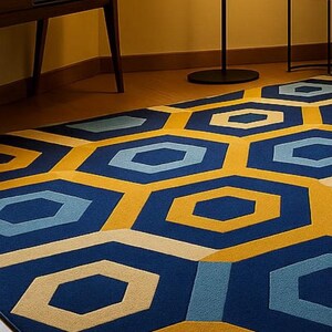 May include: A geometric patterned rug with a modern design. The rug features a repeating pattern of blue, yellow, and light blue hexagons. The rug is placed on a wooden floor, and the room has yellow walls.