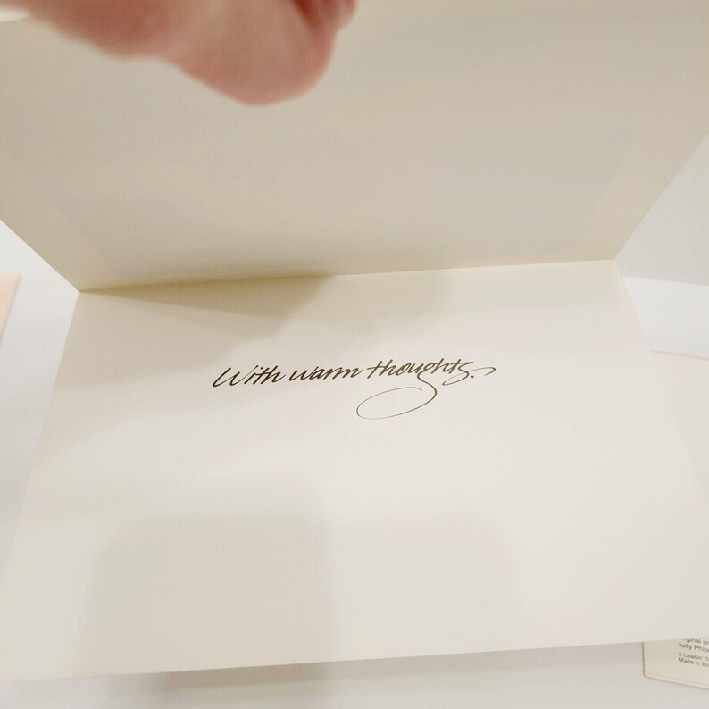 Op de afbeelding: Een open wenskaart met een cr&egrave;mekleurig interieur. De woorden "With warm thoughts" zijn geschreven in elegant zwart schrift. De kaart is opengeklapt en onthult de boodschap.