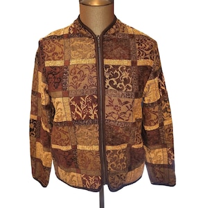 May include: A brown and gold patterned jacket with a full zipper closure. The jacket features a patchwork design with floral and scroll patterns in shades of brown, gold, and burgundy. The jacket is displayed on a mannequin.