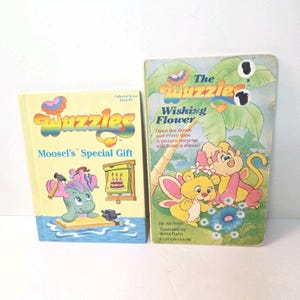 Könnte beinhalten: Zwei Vintage-Kinderbücher. Eines trägt den Titel "Moosel's Special Gift" aus der "Wuzzles" Collector Series. Das andere ist "The Wuzzles Wishing Flower". Beide Bücher enthalten farbenfrohe Illustrationen und Text.