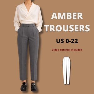 May include: Amber Trousers US 0-22. A pair of high-waisted, charcoal gray trousers with a pleated front, straight-leg silhouette, and side pockets. The trousers are paired with a cream-colored long-sleeve wrap blouse and black loafers.